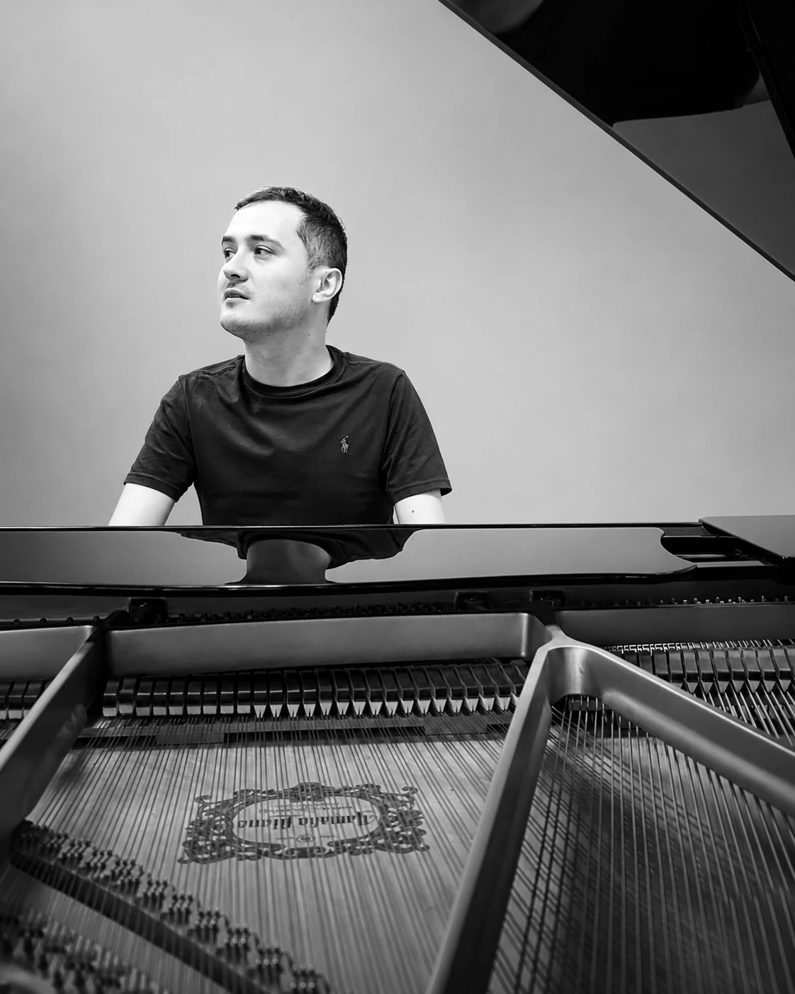 Retrato en blanco y negro de un pianista junto a un piano de cola